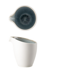 The Rosenthal Junto Aquamarine Dinnerware creamer features a white ceramic exterior with a blue-gray reactive glaze interior, curved spout, and circular design—ideal for modern table settings and safe for dishwasher and microwave use.