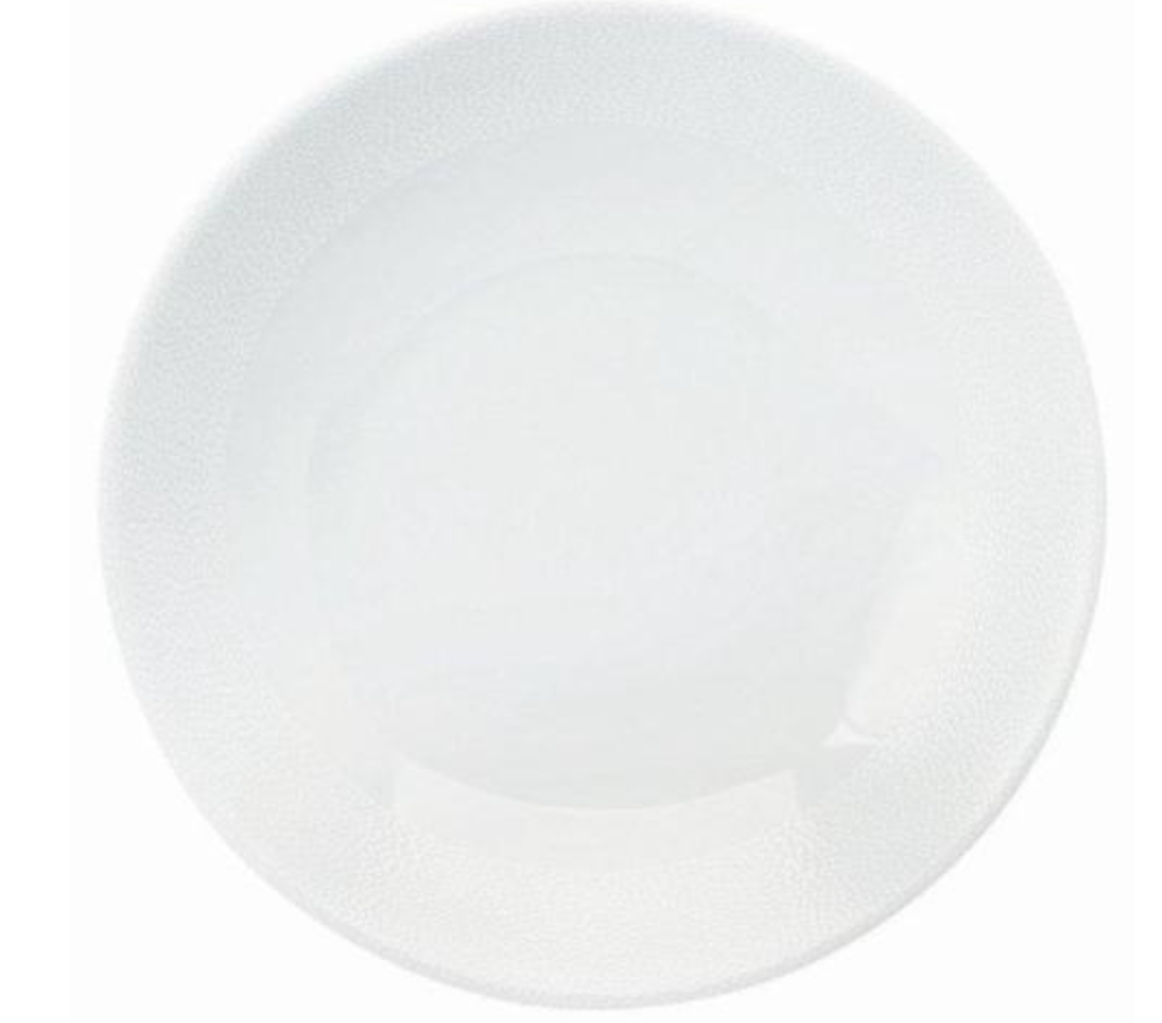 The Seychelles Dinnerware by Philippe Deshoulieres features a plain, round white ceramic plate with a slightly raised rim and smooth surface, evoking the timeless elegance of classic Limoges porcelain.