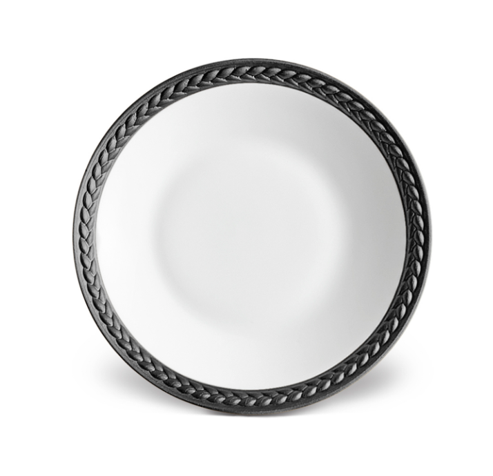 The Soie Tressée Black Dinnerware by L'Objet is a round, white luxury porcelain plate featuring a dark braided rim pattern, shown from above on a white background.