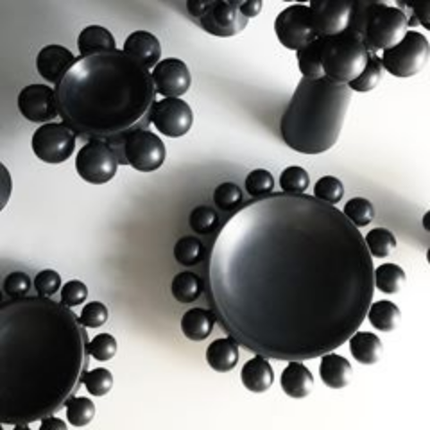 The Nimbus Halo Bowl by KleinReid—a black ceramic bowl with round bead-like rim decorations from the Nimbus Collection—is displayed on a white surface.