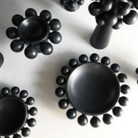 The Nimbus Halo Bowl by KleinReid—a black ceramic bowl with round bead-like rim decorations from the Nimbus Collection—is displayed on a white surface.