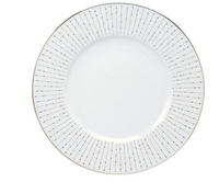 The Carrousel Dinnerware by Philippe Deshoulieres features a white Limoges porcelain plate adorned with a gold rim and fine gold lines radiating from the center, each line accented by delicate gold dots.