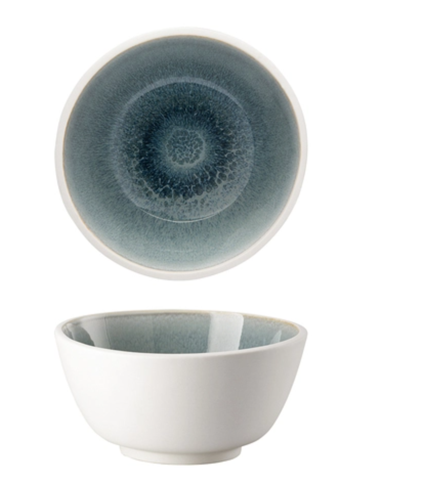 The Rosenthal Junto Aquamarine Dinnerware features a ceramic bowl with a white exterior and a blue, textured, circular interior pattern, shown from top and side views against a white background.