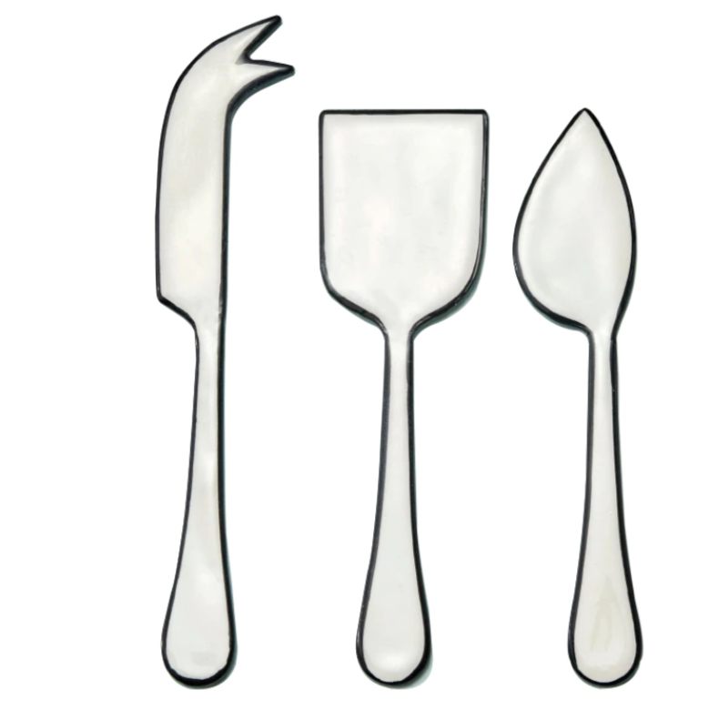 The Be Home Outline Enamel Cheese Set features three cheese knives—forked tip, rectangular blade, and triangular blade—arranged side by side on a white background. Handwash suggested.