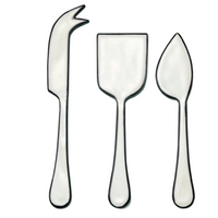 The Be Home Outline Enamel Cheese Set features three cheese knives—forked tip, rectangular blade, and triangular blade—arranged side by side on a white background. Handwash suggested.