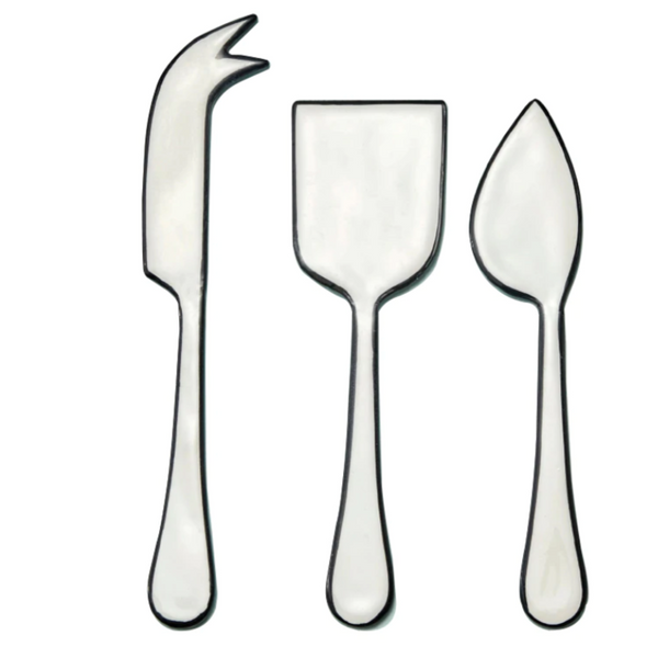 The Be Home Outline Enamel Cheese Set features three cheese knives—forked tip, rectangular blade, and triangular blade—arranged side by side on a white background. Handwash suggested.