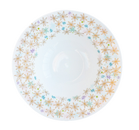 The Fèerie By Michael Cailloux plate by Bernardaud features a rim of gold, blue, and purple star-shaped flowers on fine Limoges porcelain, with a plain white center for elegant presentation.