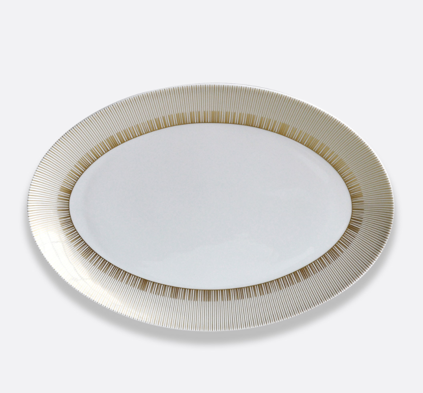 A white Limoges porcelain Sol Dinnerware plate by Bernardaud, featuring a 24k gold striped rim, is set against a plain light background.