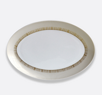 A white Limoges porcelain Sol Dinnerware plate by Bernardaud, featuring a 24k gold striped rim, is set against a plain light background.
