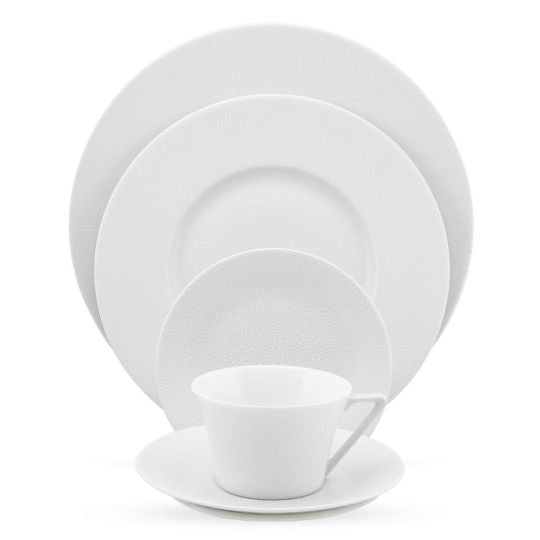 The Seychelles Dinnerware by Philippe Deshoulieres features a white teacup with saucer, small, medium, and large plates, all stacked by size against a white background.