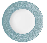 The Raynaud Mineral Irise Dinnerware Sky Blue plate, crafted in France, features a textured teal-blue rim and smooth white center—an elegant modern addition to your table.