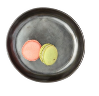 Two macarons, one pink and one green, sit side by side on the Marcus Black Dinnerware Set of 4 by Blue Pheasant, their colors contrasting elegantly against the plate’s dark surface and plain white background.
