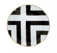 The Sol Y Sombra charger by Christian Lacroix x Vista Alegre features bold black geometric brushstrokes on white porcelain with a thin gold rim, embodying artistic elegance.