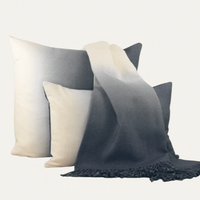 Two Johanna Howard Dip Dyed Alpaca Pillows in Pewter, featuring an ombré design, are paired with a gradient grey and white throw blanket, all set against a plain background.