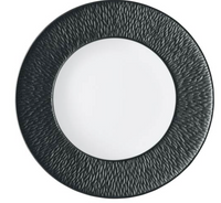 The Mineral Irise Dinnerware - Black by Raynaud features a smooth white center and a wide, textured black rim with a subtle wavy pattern. Made from Limoges porcelain, it offers a modern, minimalistic design perfect for contemporary tables.