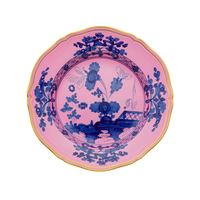 The Oriente Italiano Dinner Plate Azalea by Ginori 1735 features a scalloped edge, yellow rim, and a pink background adorned with intricate blue floral and landscape designs in the center and along the border.