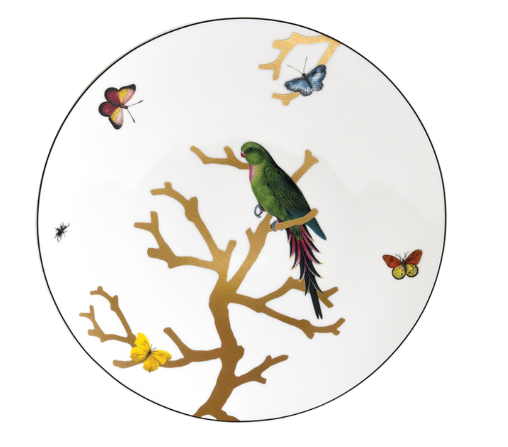 The Bernardaud Aux Oiseaux Dinnerware features a decorative Limoges porcelain plate with a green parrot on a golden branch, accented by colorful butterflies and an insect on a white background.