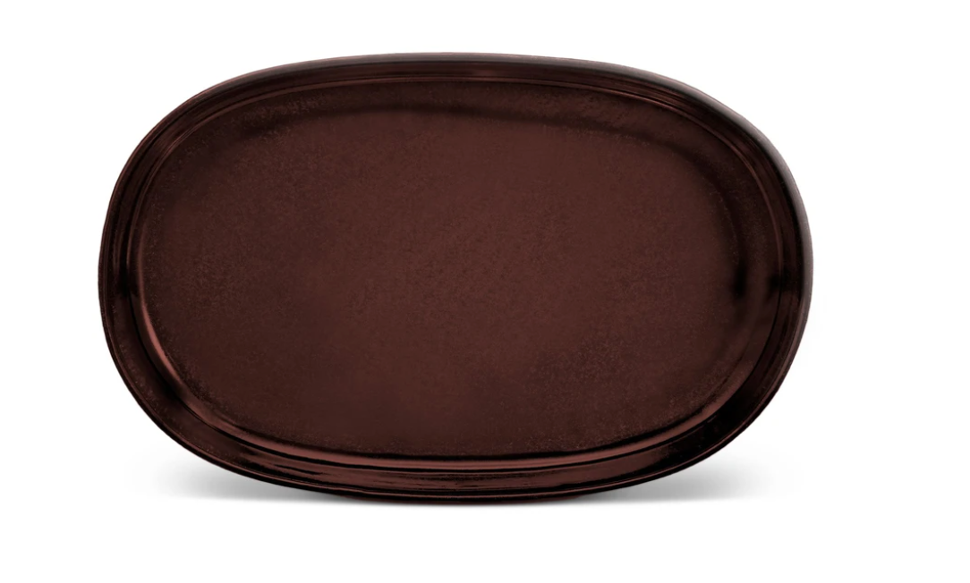 The Terra Wine Dinnerware by L'Objet is a large, oval-shaped, dark brown ceramic plate with a glossy finish, handcrafted and displayed on a plain white background.