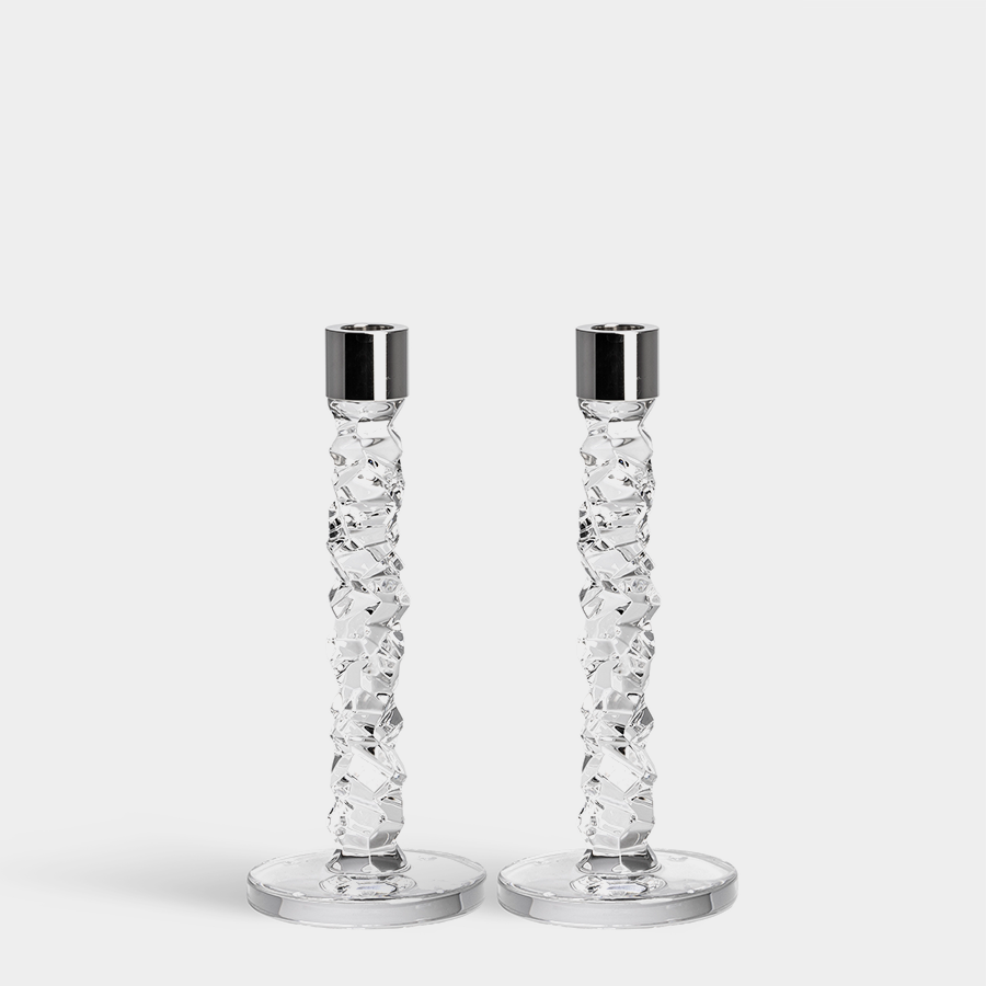 The Orrefors Kosta Boda Carat Candlesticks Silver Set of 2 features textured, faceted stems and smooth round bases with shiny silver candle cups, standing side by side on a plain white background.