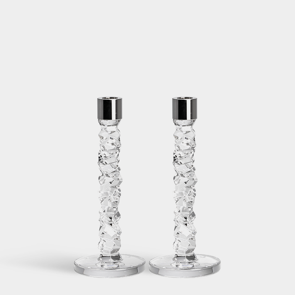 The Orrefors Kosta Boda Carat Candlesticks Silver Set of 2 features textured, faceted stems and smooth round bases with shiny silver candle cups, standing side by side on a plain white background.