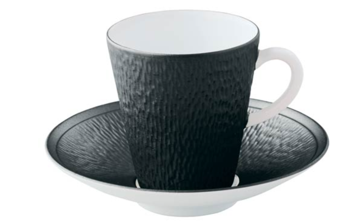 The Raynaud Mineral Irise Dinnerware - Black features a textured black porcelain coffee cup with a white interior on a matching saucer, highlighting modern elegance against a crisp white background.