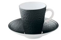 The Raynaud Mineral Irise Dinnerware - Black features a textured black porcelain coffee cup with a white interior on a matching saucer, highlighting modern elegance against a crisp white background.