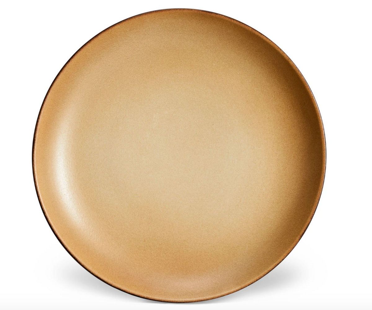 The L'Objet Terra Leather Dinnerware plate features a round shape, tan color with a subtle gradient, and glazed finish, shown against a white background.
