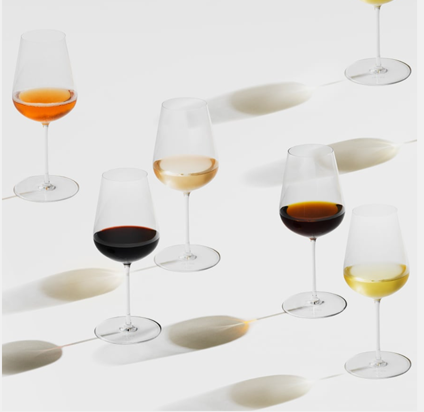 Two Richard Brendon Jancis Robinson Universal Wine Glasses, each filled with red, rosé, white, and amber wines, rest on a white surface and cast graceful oval shadows in different directions.