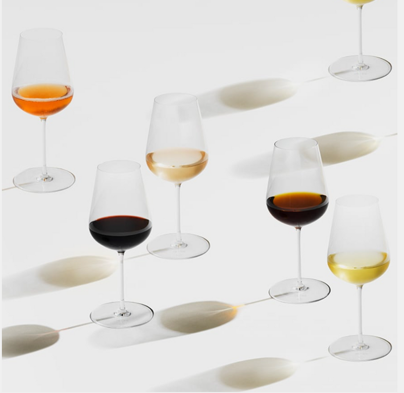 Two Richard Brendon Jancis Robinson Universal Wine Glasses, each filled with red, rosé, white, and amber wines, rest on a white surface and cast graceful oval shadows in different directions.