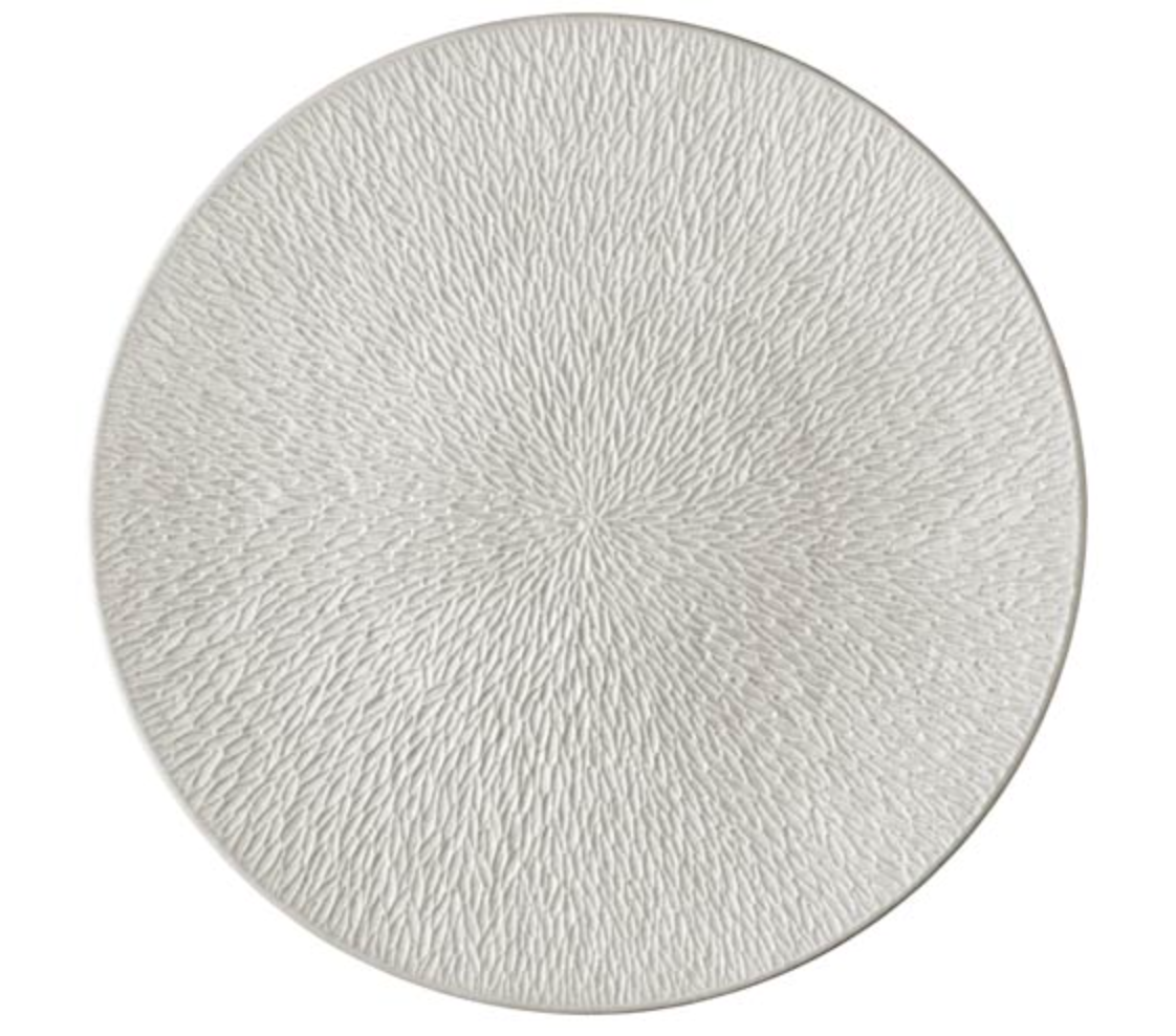 The Mineral Irise Dinnerware Pearl Grey by Raynaud is a round, pearl grey Limoges porcelain plate with a textured surface featuring a fine, radiating pattern of small, overlapping ridges.