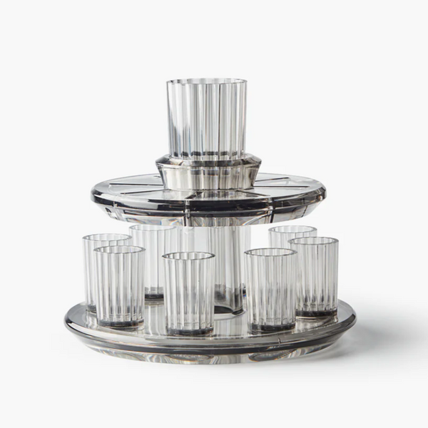 The Apeloig Kiddush Wine Fountain Set features eight ribbed clear glasses on a two-tiered fountain with a central Kiddush Cup, all crafted from transparent material—an elegant addition to your Judaica collection.