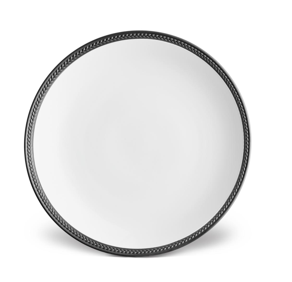 The Soie Tressée Black Dinnerware by L'Objet features a round, white ceramic plate with a dark braided rim, echoing luxury porcelain styles, displayed on a plain white background.
