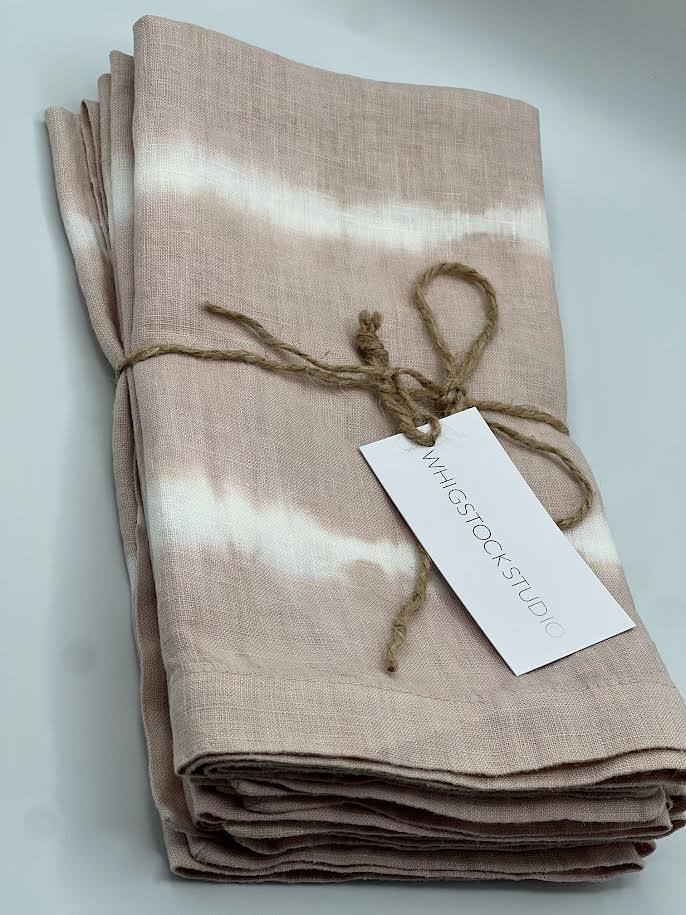 A folded, dusty rose hand dyed linen napkin from Whigstock Studio is tied with twine and labeled, shown on a white background. Set of 4.