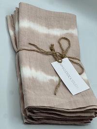 A folded, dusty rose hand dyed linen napkin from Whigstock Studio is tied with twine and labeled, shown on a white background. Set of 4.