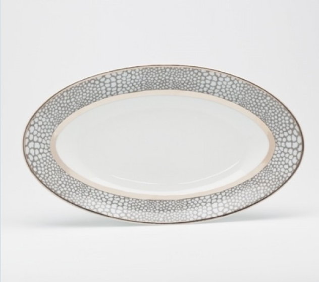 The Makassar Gray & Platinum Dinnerware by Royal Limoges/Bia Cordon Bleu is an oval porcelain plate handmade in France, featuring a gray and white textured rim with a platinum accent on a white background.