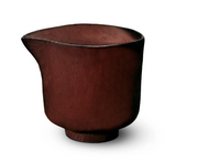 The L'Objet Terra Wine Dinnerware bowl features a rustic, reddish-brown hue and an irregular, curved rim. Its matte, textured surface adds charm—perfect for mixing with your favorite handcrafted pieces.