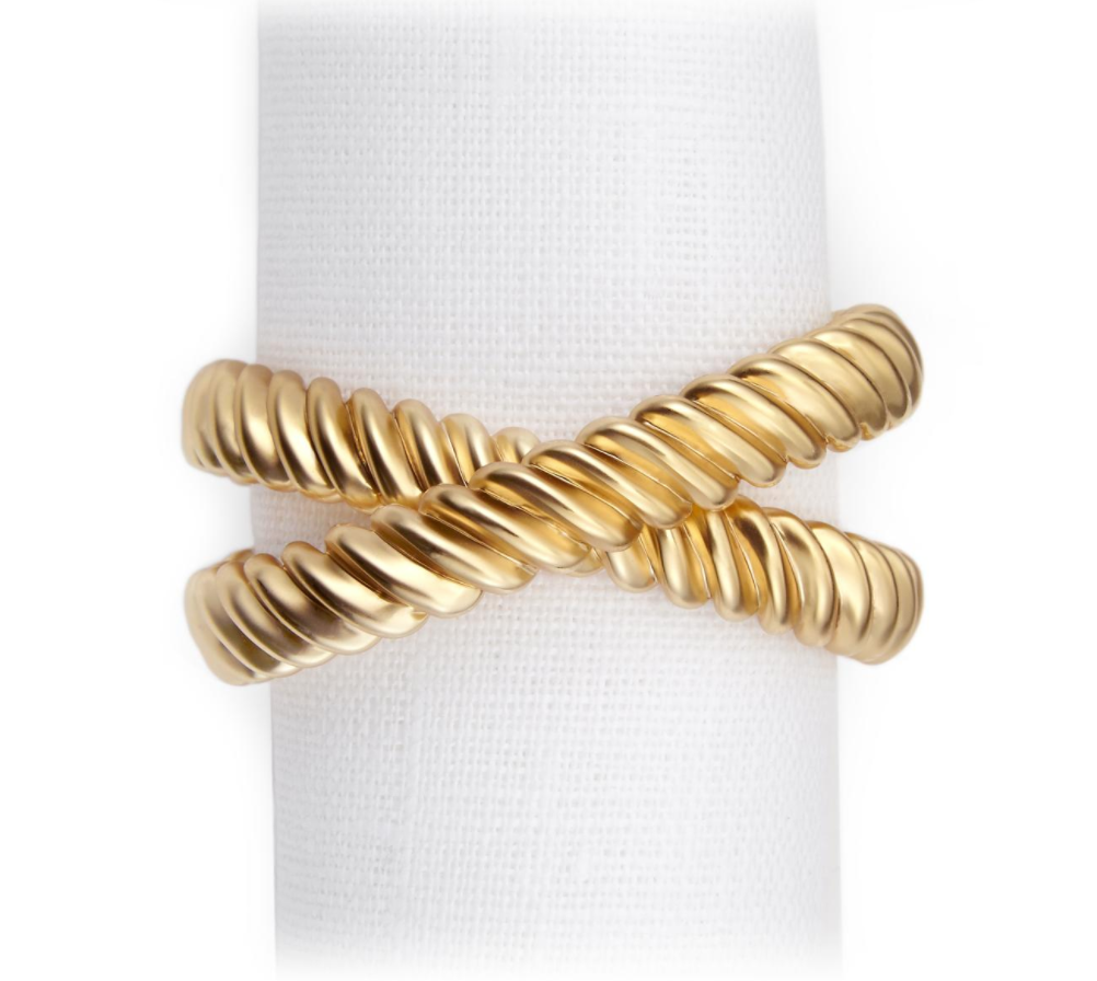 The L'Objet Deco Twist Napkin Ring Set of 4 features 24K gold-plated, ribbed double-band rings with a twisted rope X design, displayed on a white textured background, reminiscent of luxury table settings.