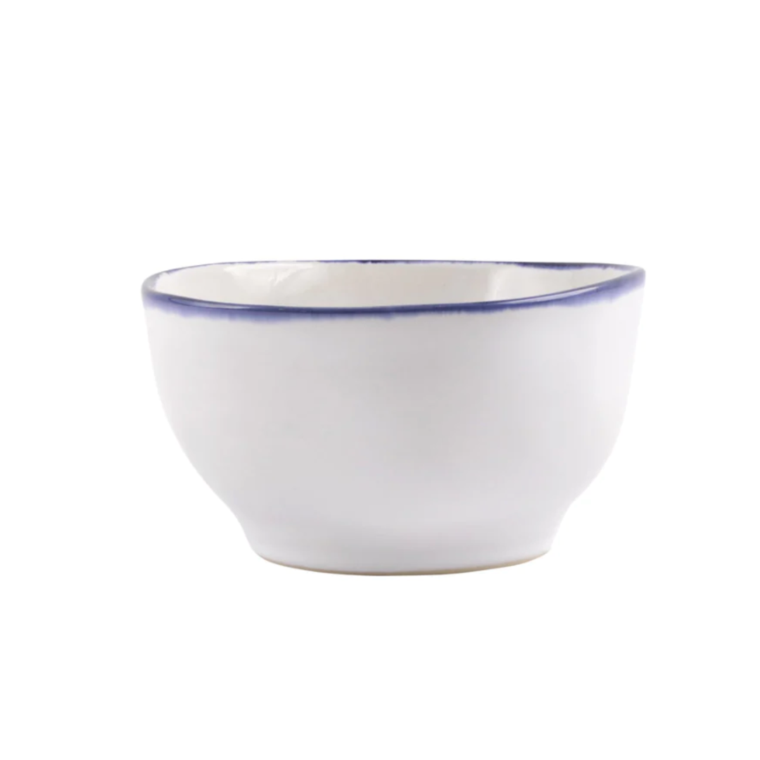 The Vietri Aurora Edge Dinnerware bowl is handmade in Italy from white stoneware with a subtle blue rim and is chip resistant, shown against a plain white background.