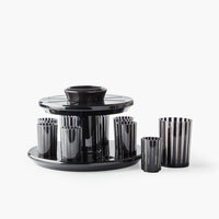 The Apeloig Kiddush Wine Fountain Set features sleek black and clear striped glasses around a matching circular tray and central holder, blending modern Judaica design with a glossy finish for stylish wine serving.