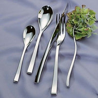 The Couzon/DeVine Corp MAISON3AMIS Steel Flatware 5 Piece Setting, arranged on lilac satin beside a small hydrangea, includes two spoons, a knife, and a fork—all in polished stainless steel.
