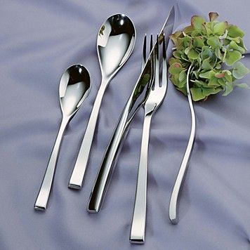 The Couzon/DeVine Corp MAISON3AMIS Steel Flatware 5 Piece Setting, arranged on lilac satin beside a small hydrangea, includes two spoons, a knife, and a fork—all in polished stainless steel.