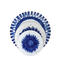 Four white plates from the Bernardaud In Bloom Dinnerware collection are stacked, each showcasing unique blue radial patterns reminiscent of abstract florals or starbursts.