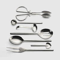 The Mary Jurek Versa Meat Serving Fork features a shiny, silver hammered design, perfect for stylish serving; it's part of the elegant Versa collection of specialized serving utensils.