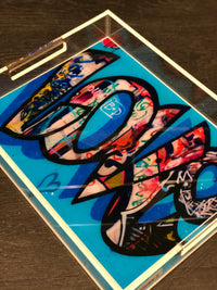 The Eye Candy Graffiti Love Tray | Limited Edition features Chelsea Beck's vibrant graffiti-style "LOVE" art on clear acrylic with a bold blue background, shown on a dark wooden surface.