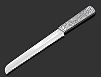 The Organic Lace Challah Knife Silver by Metalace Art features a serrated, shiny blade and a metal lace-patterned handle—an elegant piece displayed on dark gray, perfect as a memorable wedding gift.