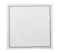 The Kim Seybert Filament Napkin White & Gunmetal Set of 4 features square white linen napkins with a simple gunmetal stitched border, displayed flat against a white background.