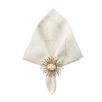The Kim Seybert Star Spray Napkin White & Gold & Silver Set of 4 features elegant white linen napkins with subtle dots, each adorned with a decorative gold sunburst ring for a sophisticated table setting.