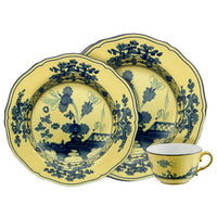 The Ginori 1735 Oriente Italiano Dinnerware Citrino set includes two plates with floral patterns and a handled teacup, all featuring intricate blue designs on a yellow porcelain background in a striking chinoiserie style.