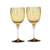 A Perle Wine Goblet Set of 2 by Zafferano, featuring amber bowls with dotted textures and clear stems, is displayed side by side on a white background. Made in Italy.
