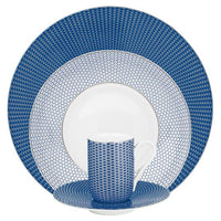 The Raynaud Tresor Dinnerware Blue set includes four elegant porcelain pieces—a dinner plate, salad plate, cup, and saucer—adorned with blue and white geometric patterns for a refined dining experience.
